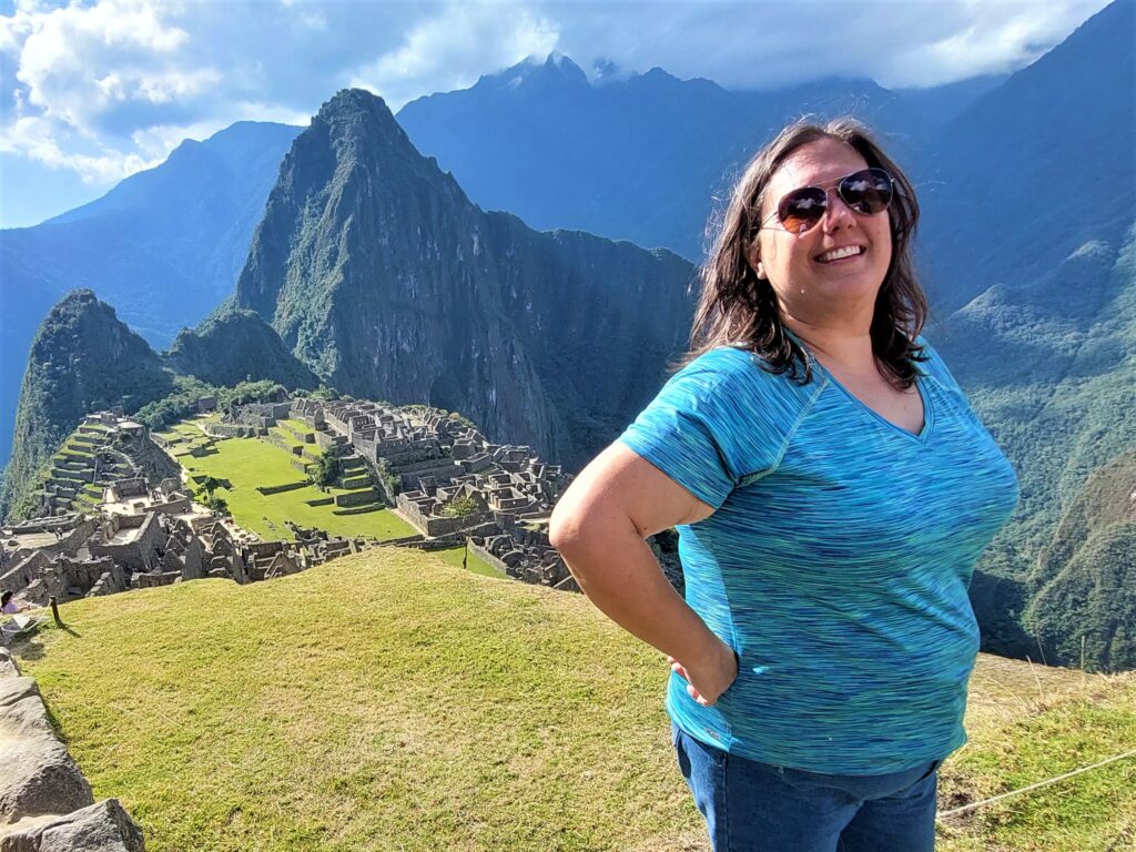 Brodi smiling overlooking Machu Picchu in Peru. Build fun stuff into your digital nomad budget.