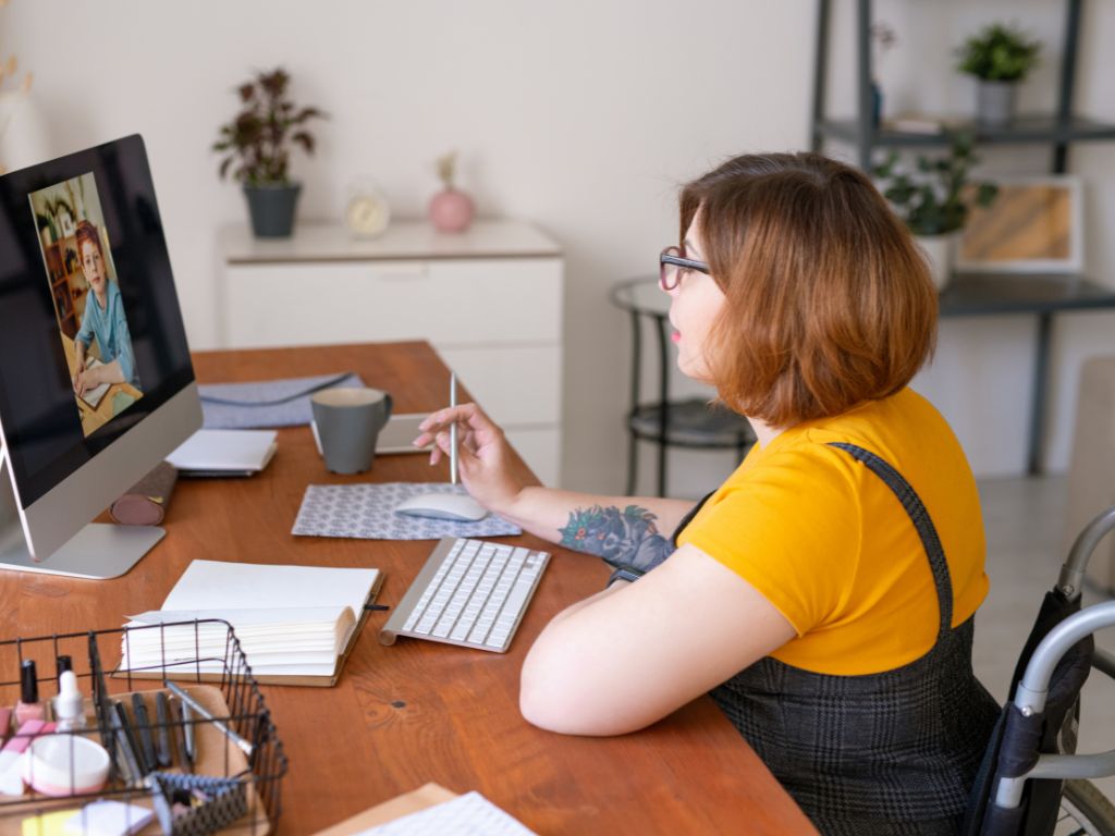 woman in a wheelchair sitting at a computer in a home office