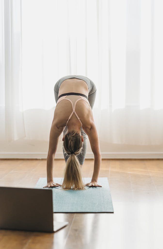 Flexible anonymous woman practicing uttanasana at home