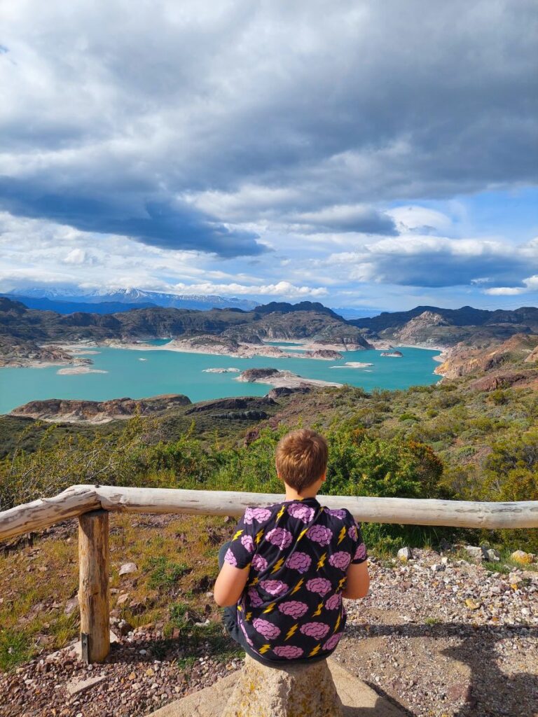 LIttle Man overlooking a turquoise lake with snowcapped mountains in the background on the Carretera Austral in Chile.